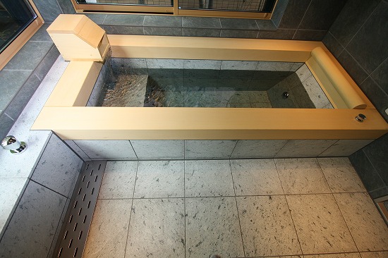 框には、ご要望により厚さ100mmの無垢の天然ヒノキを使用し、浴槽の内部には天然十和田石を使用しています。