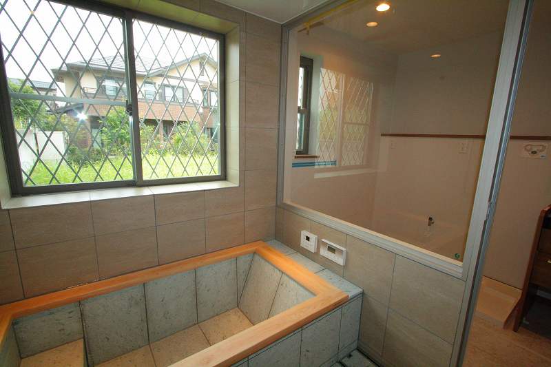 洗面室との間仕切りに透明ガラスを組み込んだアルミ枠FIXを。