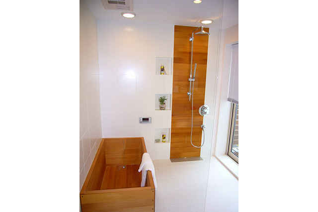 浴槽と壁のアクセントは、天然ヒバ材を採用しています。人工乾燥(エステック処理)の温度を上げ焦がし色に仕上げました。