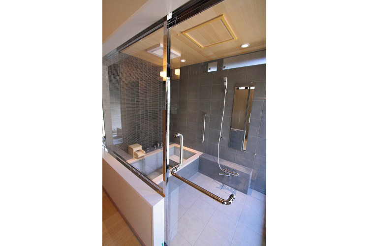 洗い場カウンターの右端は、大きなはき出しのドアを設置するため短くカットしています。入り口ドアは、ステンレス製フレームの透明強化ガラス仕様です。広々感が増します。