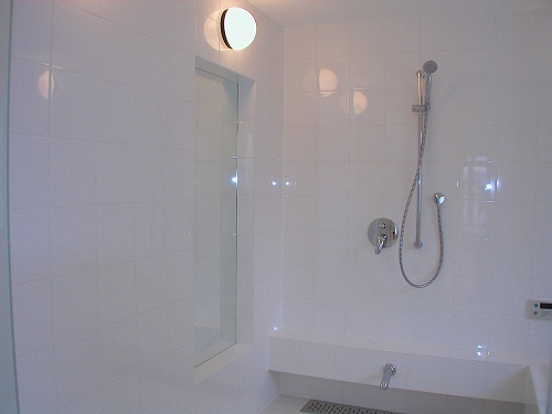 鏡は、バスルームの壁にニッチ収納を創り、その中に。