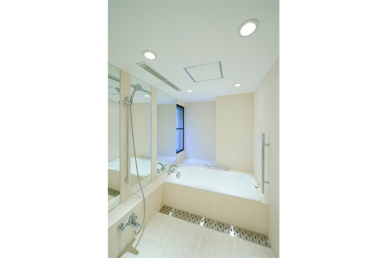 壁はベージュの天然大理石仕上げ。床は、ひんやり度が低いサーモタイル。鋳物ホーロー浴槽のピュアなホワイトが綺麗なバスルーム。