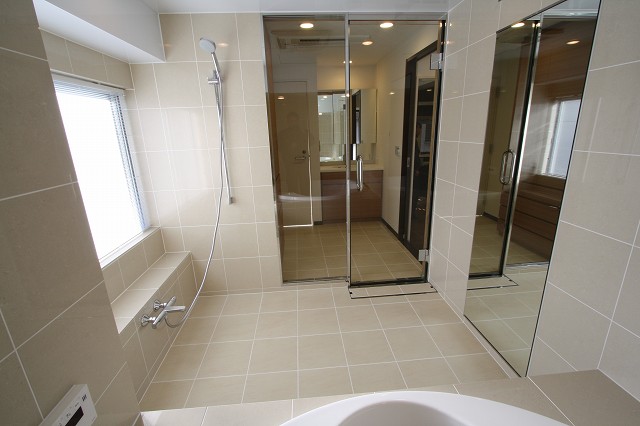 洗面室との間仕切りは透明強化ガラスを採用しました。洗面室用のサーモタイル採用で浴室と一体感が。