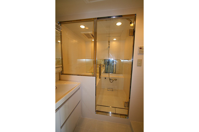 透明ガラスで狭いバスルームに開放感を。洗面室の壁と床は浴室と同じタイルを使用し、一体感を持たせました。