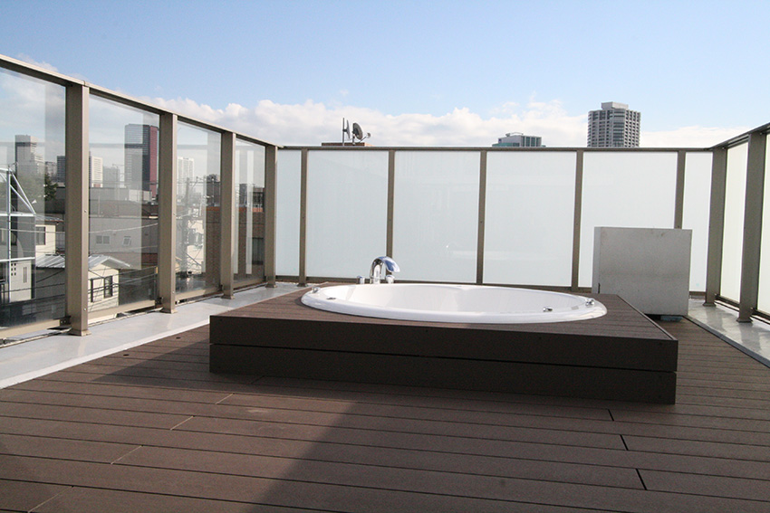 高層ビルが見渡せる住宅の屋上で、ジャグジーバスを楽しむ