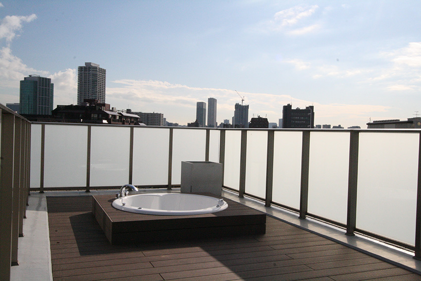 高層ビルが見渡せる住宅の屋上で、ジャグジーバスを楽しむ