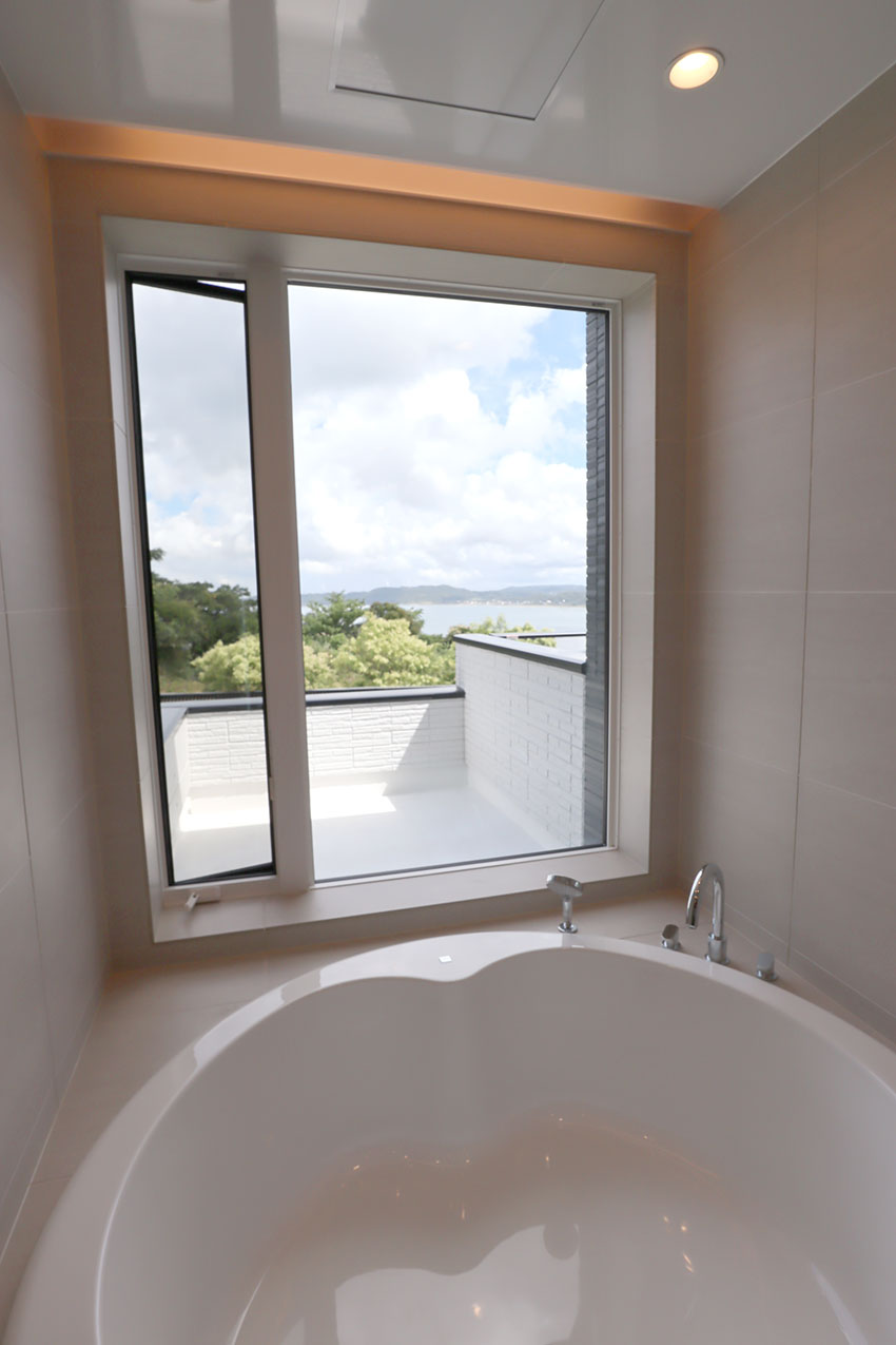 浴室の窓から見える大海原 円形浴槽とオーバーヘッドシャワーそして透明ガラスドア
