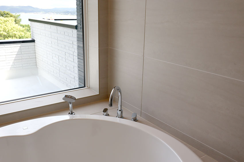 浴室の窓から見える大海原 円形浴槽とオーバーヘッドシャワーそして透明ガラスドア